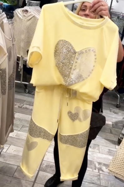 Prosty top z dekoltem w kształcie serca ozdobionym cekinami w połączeniu ze spodniami ozdobionymi serduszkami i cekinami.