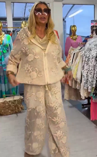 Damski kostium składa się z bluzy z kapturem ozdobionej eleganckim kwiatowym wzorem oraz szerokich spodni.