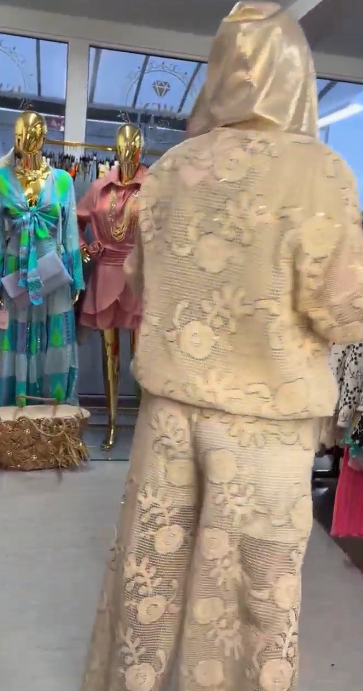 Damski kostium składa się z bluzy z kapturem ozdobionej eleganckim kwiatowym wzorem oraz szerokich spodni.