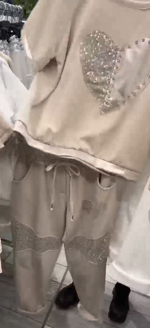 Prosty top z dekoltem w kształcie serca ozdobionym cekinami w połączeniu ze spodniami ozdobionymi serduszkami i cekinami.