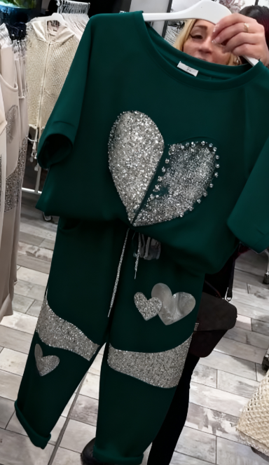 Prosty top z dekoltem w kształcie serca ozdobionym cekinami w połączeniu ze spodniami ozdobionymi serduszkami i cekinami.
