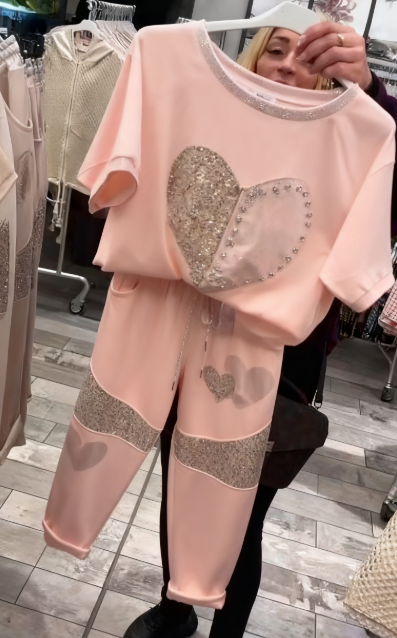 Prosty top z dekoltem w kształcie serca ozdobionym cekinami w połączeniu ze spodniami ozdobionymi serduszkami i cekinami.