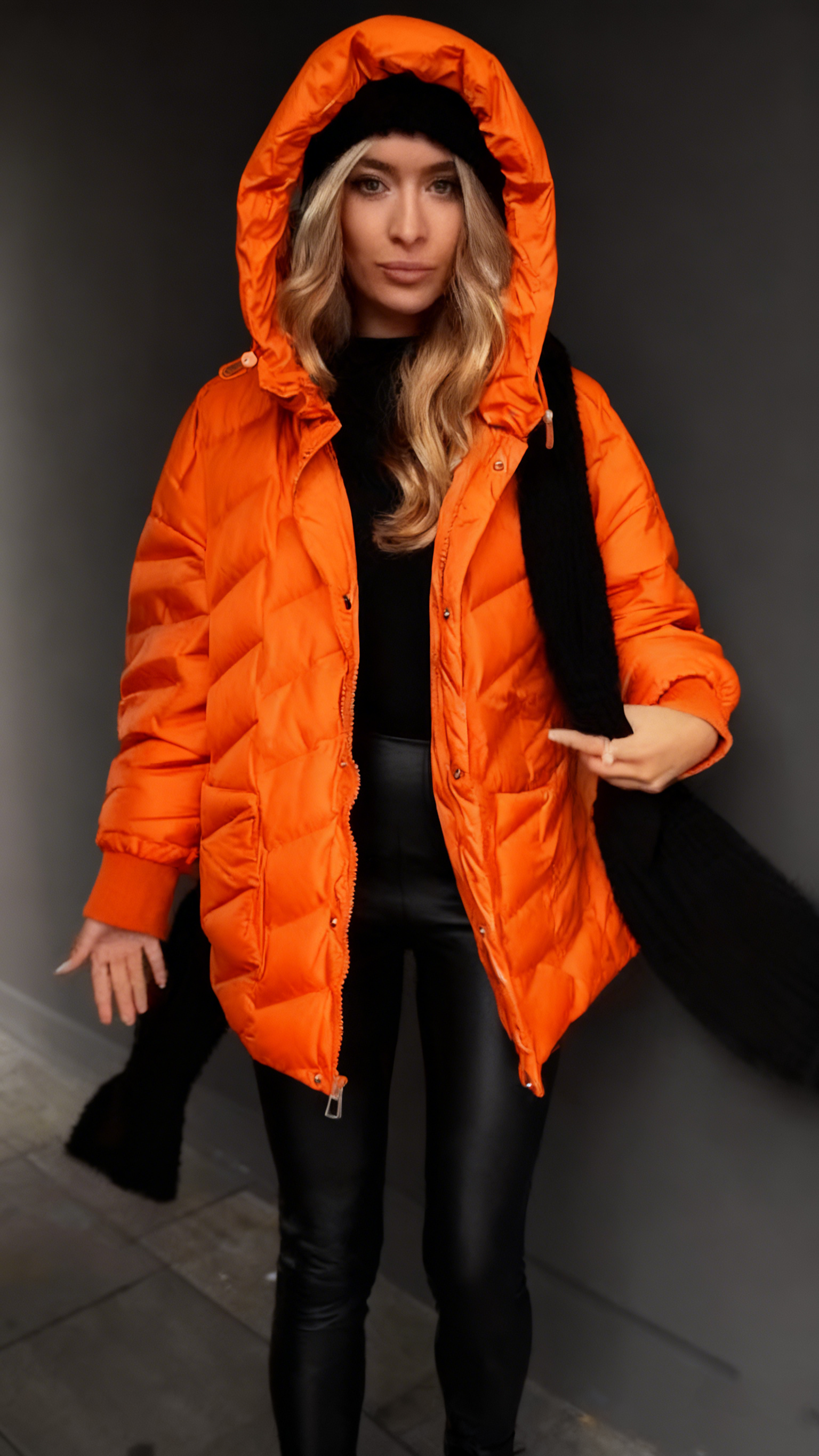 Kurtka puchowa z kapturem i fakturowaną fakturą, sięgająca do połowy łydki.