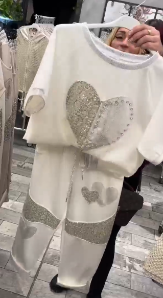 Prosty top z dekoltem w kształcie serca ozdobionym cekinami w połączeniu ze spodniami ozdobionymi serduszkami i cekinami.