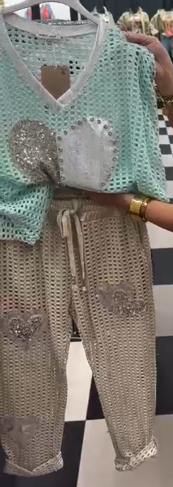 Strój składający się z koszuli z dekoltem w serek i spodni, ozdobiony wyjątkowymi wycięciami i cekinowymi sercami.