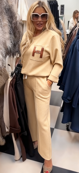 Strój składający się z bluzki ozdobionej ozdobnymi detalami w kształcie litery „H” oraz wygodnych spodni z kieszeniami.