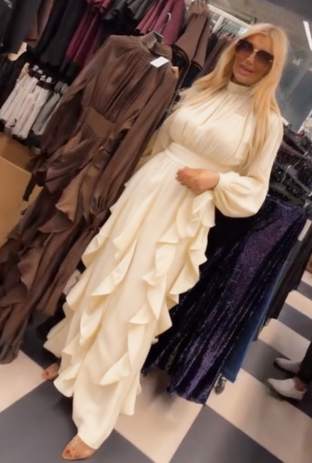 Sukienka ta charakteryzuje się licznymi falbanami w talii i plisowanymi długimi rękawami.