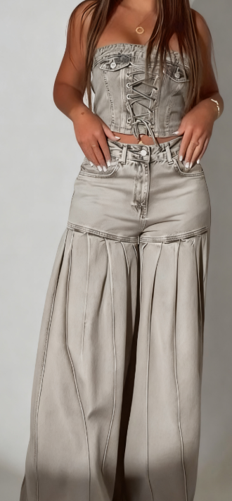 Stylowy strój składający się z jeansowego topu bez ramiączek i pasującej do niego pary plisowanych jeansów z szerokimi nogawkami.