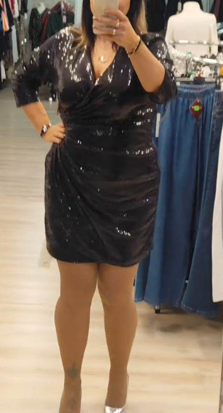 Sukienka z cekinowymi detalami, głębokim dekoltem w serek i rękawami o długości do połowy łydki.