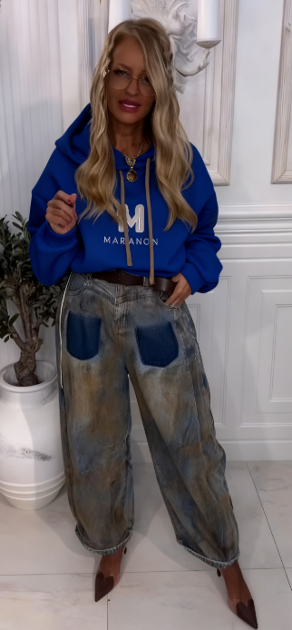 Bluza z kapturem z wyjątkowym wzorem liter w połączeniu z luźnymi jeansami w kontrastujących kolorach.