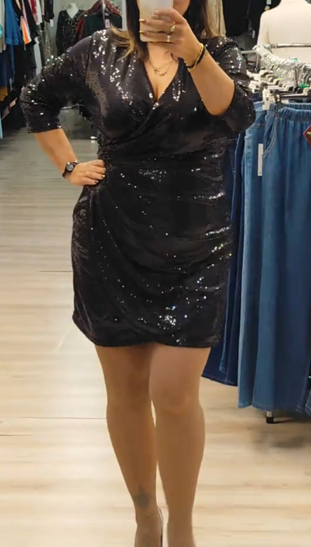 Sukienka z cekinowymi detalami, głębokim dekoltem w serek i rękawami o długości do połowy łydki.