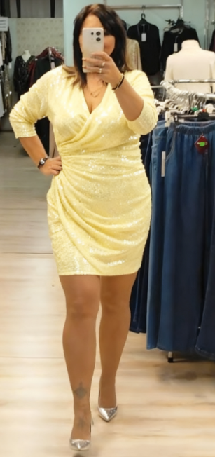 Sukienka z cekinowymi detalami, głębokim dekoltem w serek i rękawami o długości do połowy łydki.