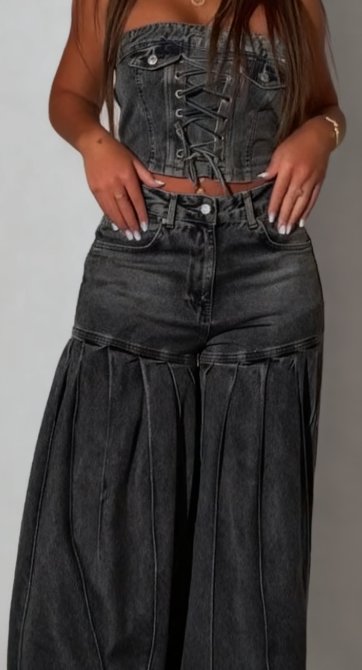 Stylowy strój składający się z jeansowego topu bez ramiączek i pasującej do niego pary plisowanych jeansów z szerokimi nogawkami.