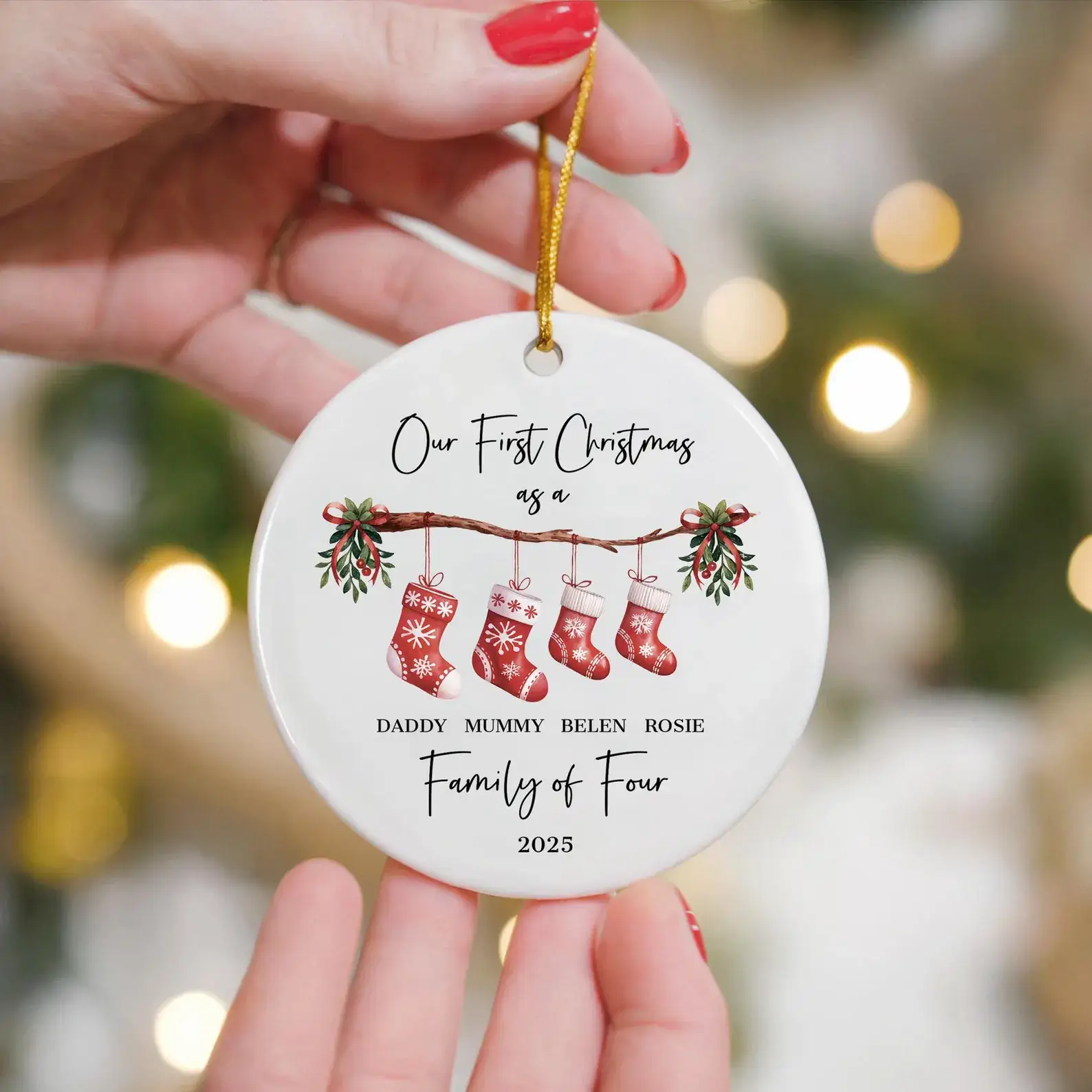 Woman holding a personalised 'First Christmas as a Family of 4' ornament in a festive Christmas setting
