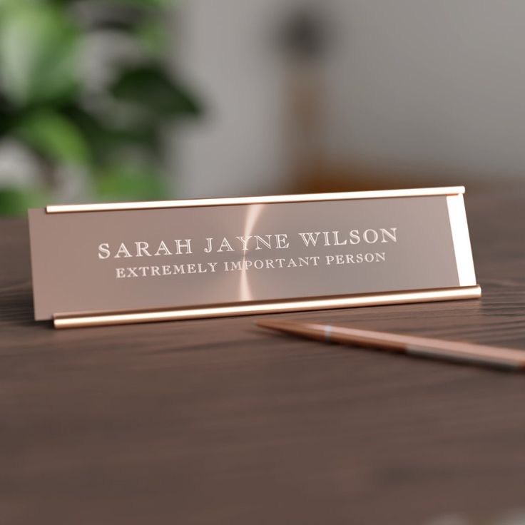 A sleek metal desk name plate with brushed finish and engraved lettering, giving a modern and professional appearance on the desk.