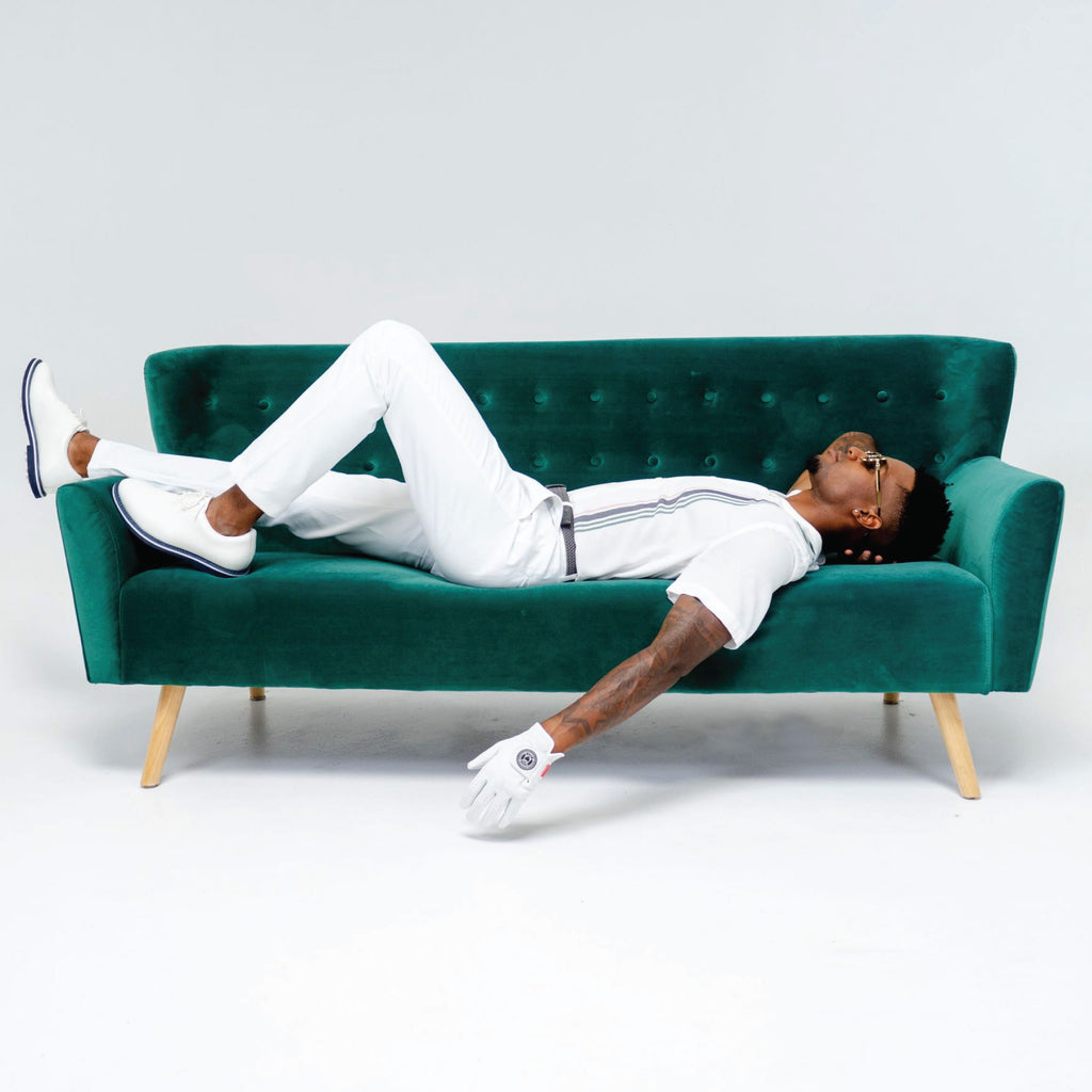Ghost Golf White Glove. Male lying down on Green Sofa. Wearing White Pant and Shirt. Wearing White Glove