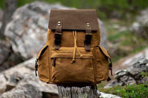 new men and women khaki waxed canvas laptop backpack sitting on a wood branch during camping mission