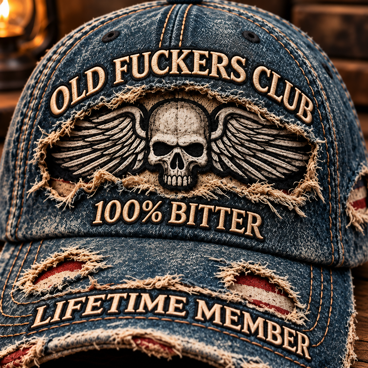Close-up of the winged skull, tan embroidery, frayed blue fabric and striped fabric visible through the brim openings