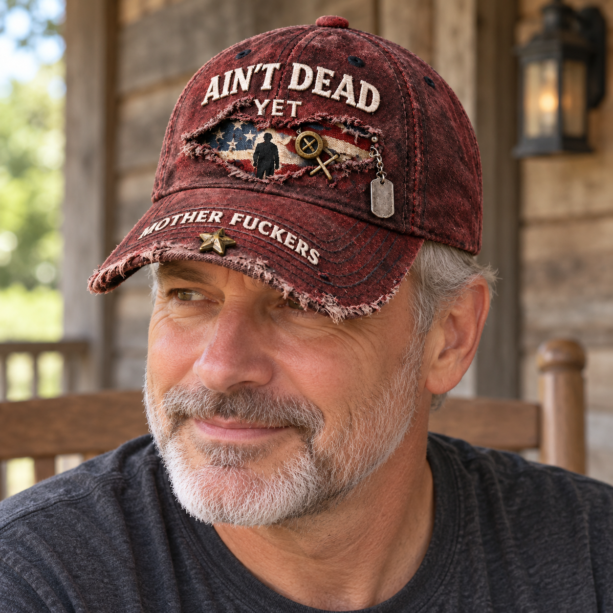 An adult man wearing the weathered red Ain’t Dead Yet cap outdoors with a casual charcoal shirt