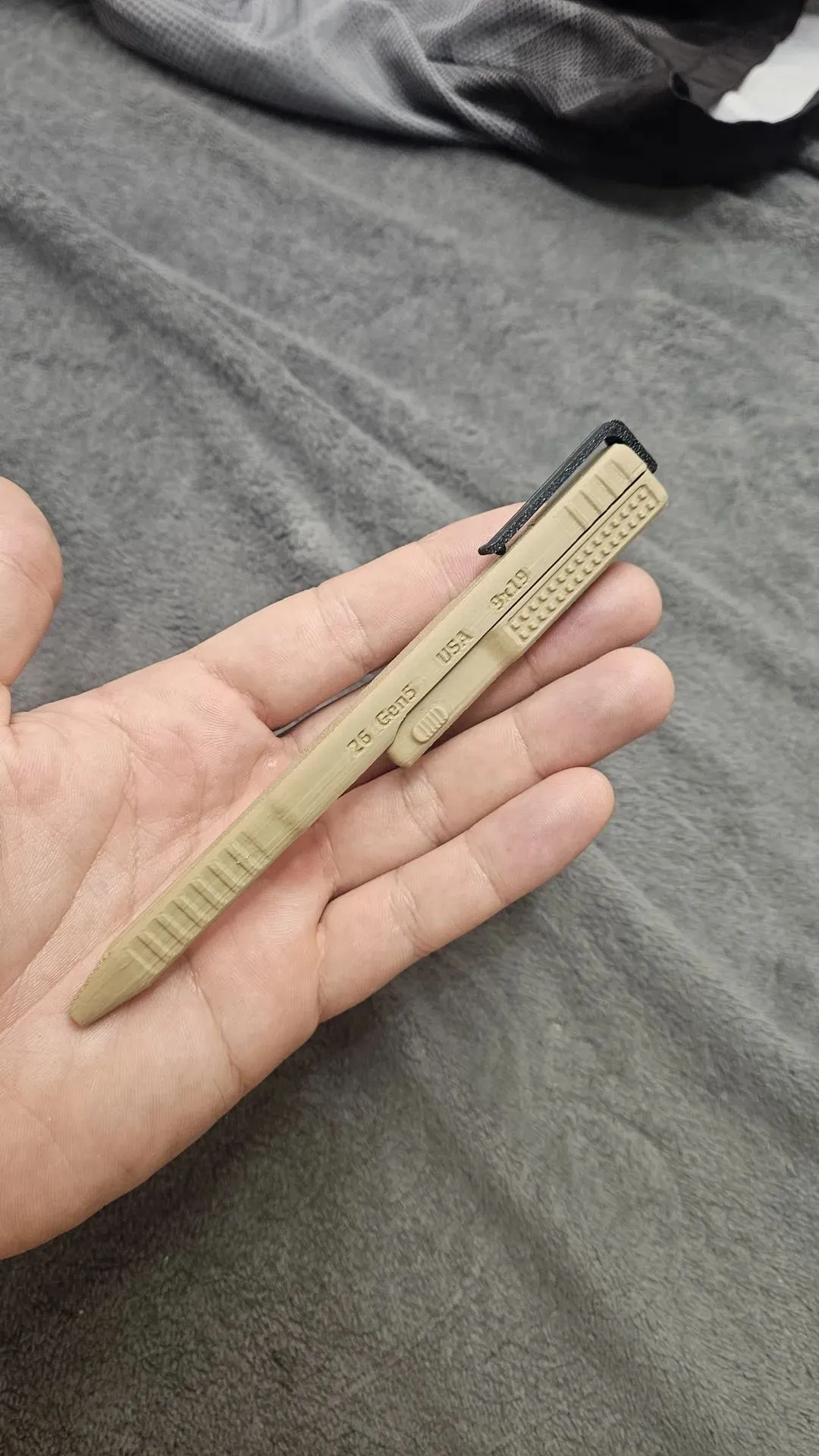 Khaki color tactical-inspired novelty pen shown in hand