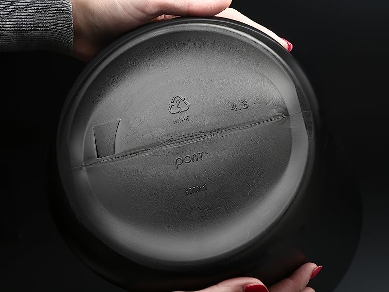 Mani che tengono un piatto o un piatto rotondo di colore scuro con un disegno in rilievo