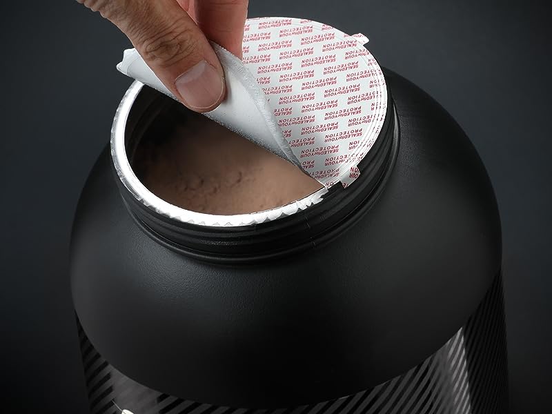 Primo piano di un contenitore nero arrotondato con un sigillo bianco che viene rimosso, rivelando una sostanza marrone all'interno. Superficie ruvida visibile