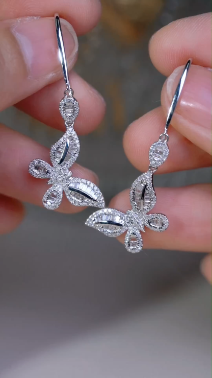 18-karat gold earrings in the shape of a butterfly, featuring a natural diamond of 0.70 carats set in a tapered baguette cut within a channel setting.
