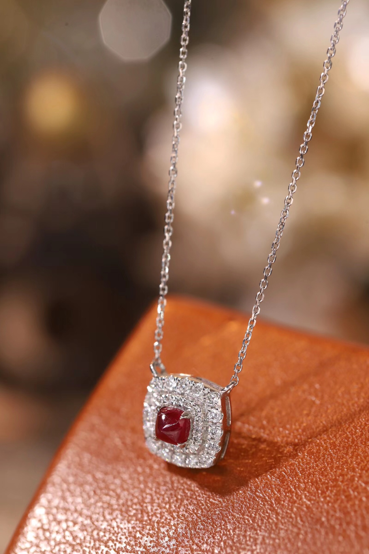This 18K gold necklace is adorned with a 0.22-carat natural ruby, as well as tiny natural diamonds totaling 0.18 carats; the ruby in question has an oval shape.