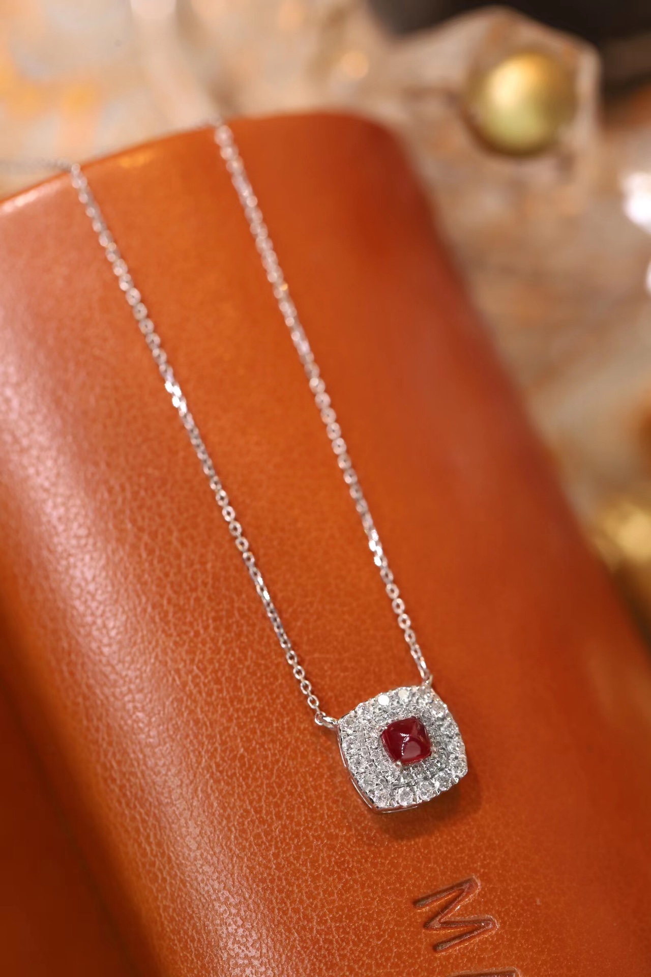 This 18K gold necklace is adorned with a 0.22-carat natural ruby, as well as tiny natural diamonds totaling 0.18 carats; the ruby in question has an oval shape.