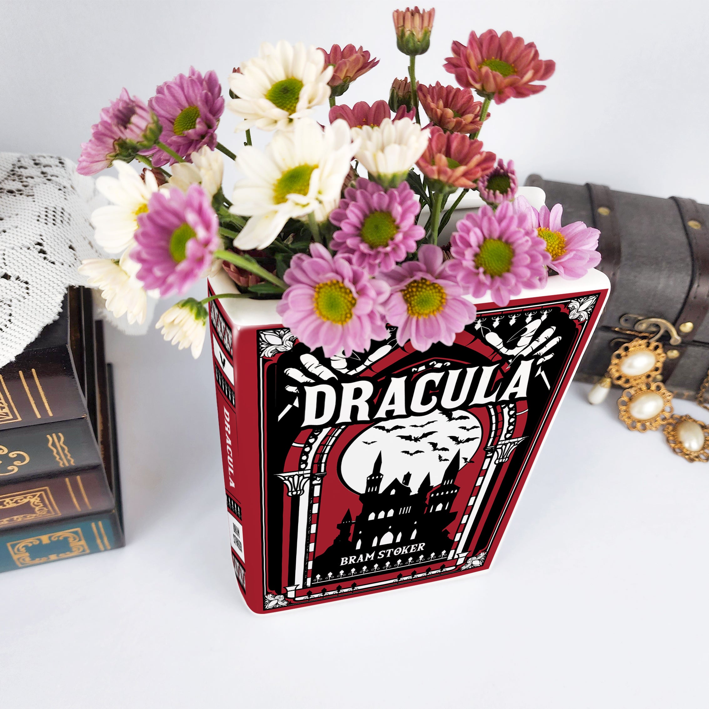 Dracula ceramic book vase with pink and white flowers, vintage books, and jewelry box