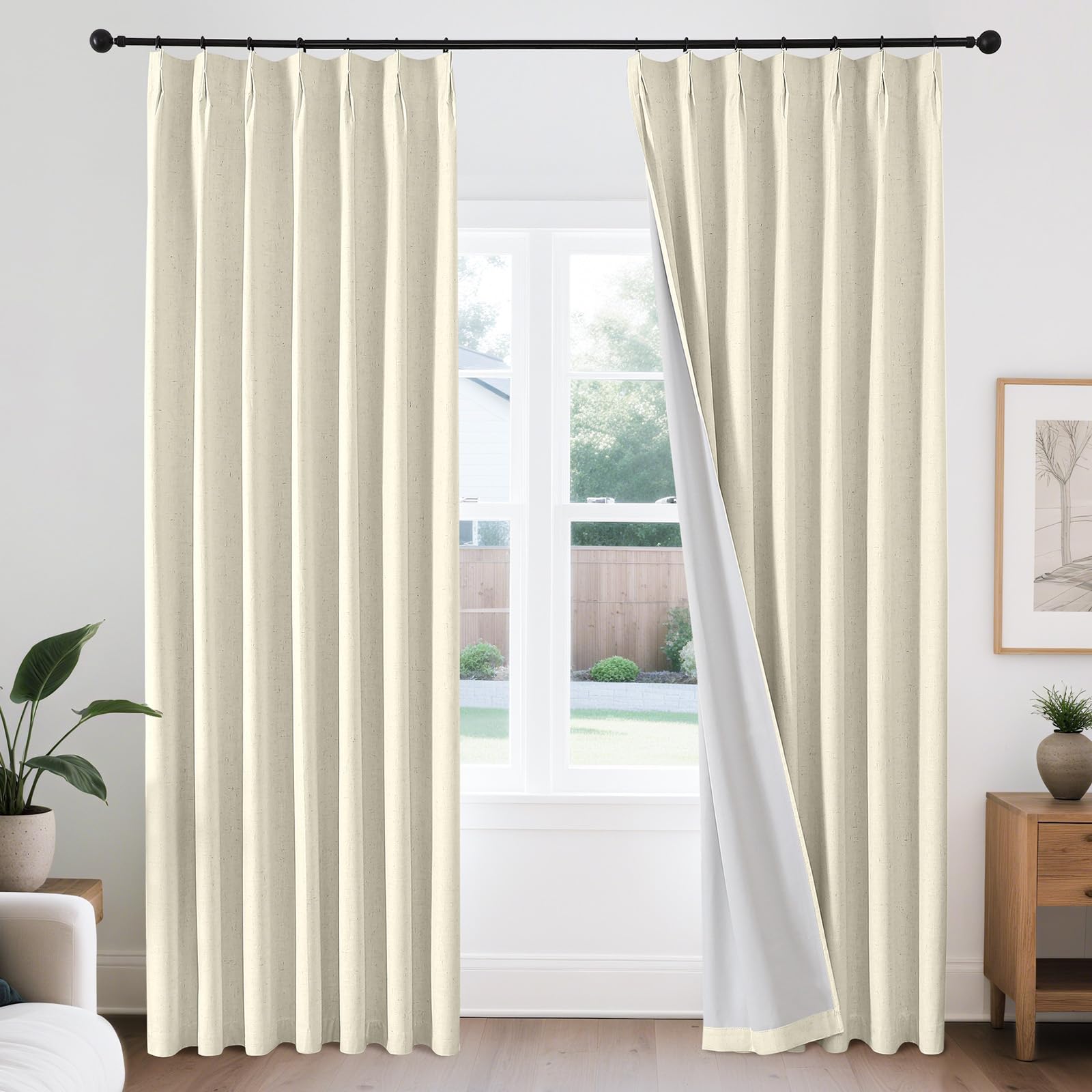 Joydeco beige linen pinch pleat blackout curtains with white thermal lining on black rod, one panel pulled back.