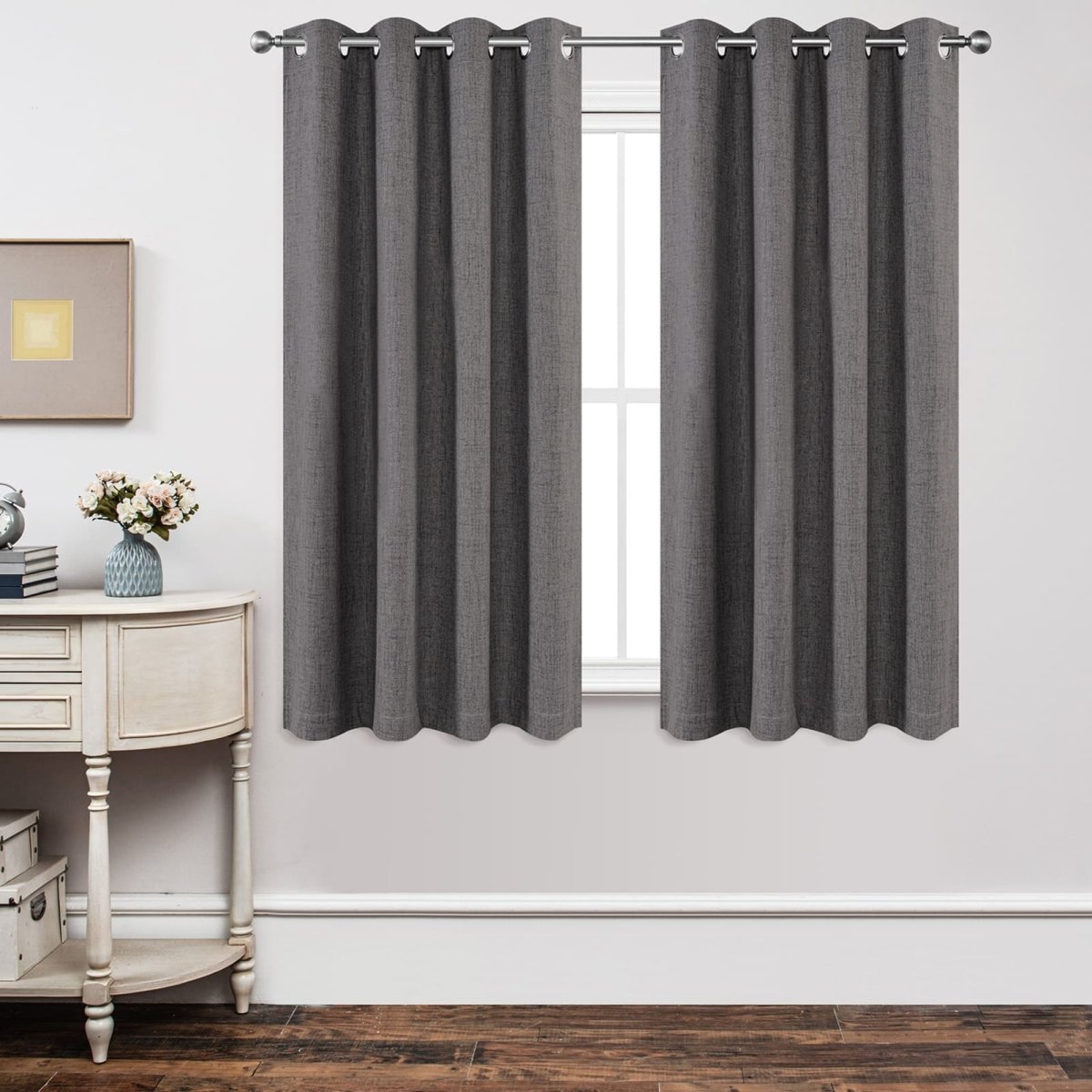 Two dark grey linen blackout curtains with grommets hang across a window, showcasing room decor and privacy.