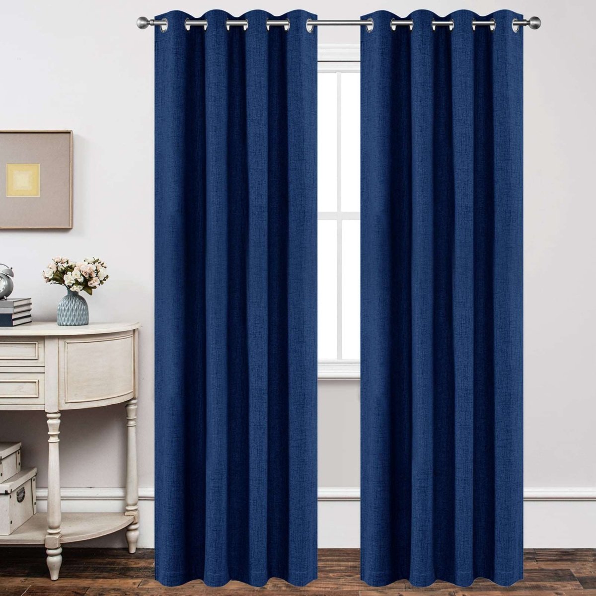 Navy blue linen blackout curtains with textured weave and grommet tops hanging on a silver rod in a room setting.