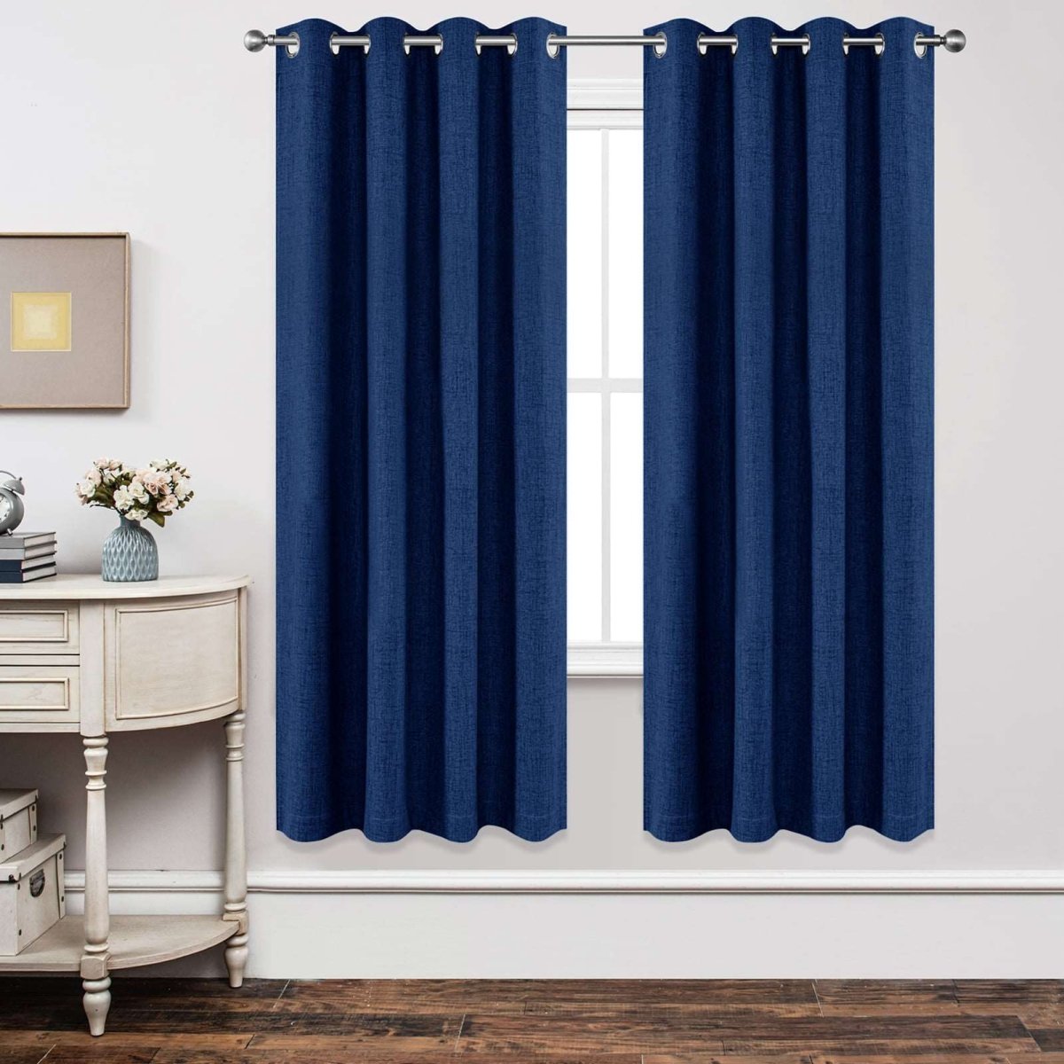 Navy blue linen blackout curtains hung on silver rod over white window, showcasing product.