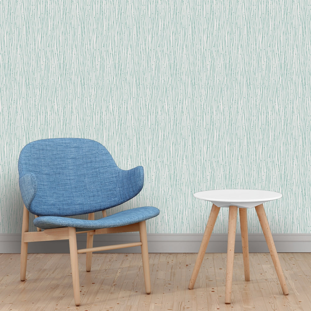 A blue chair and white end table with Tempaper's String of Pearls Removable Wallpaper in green.