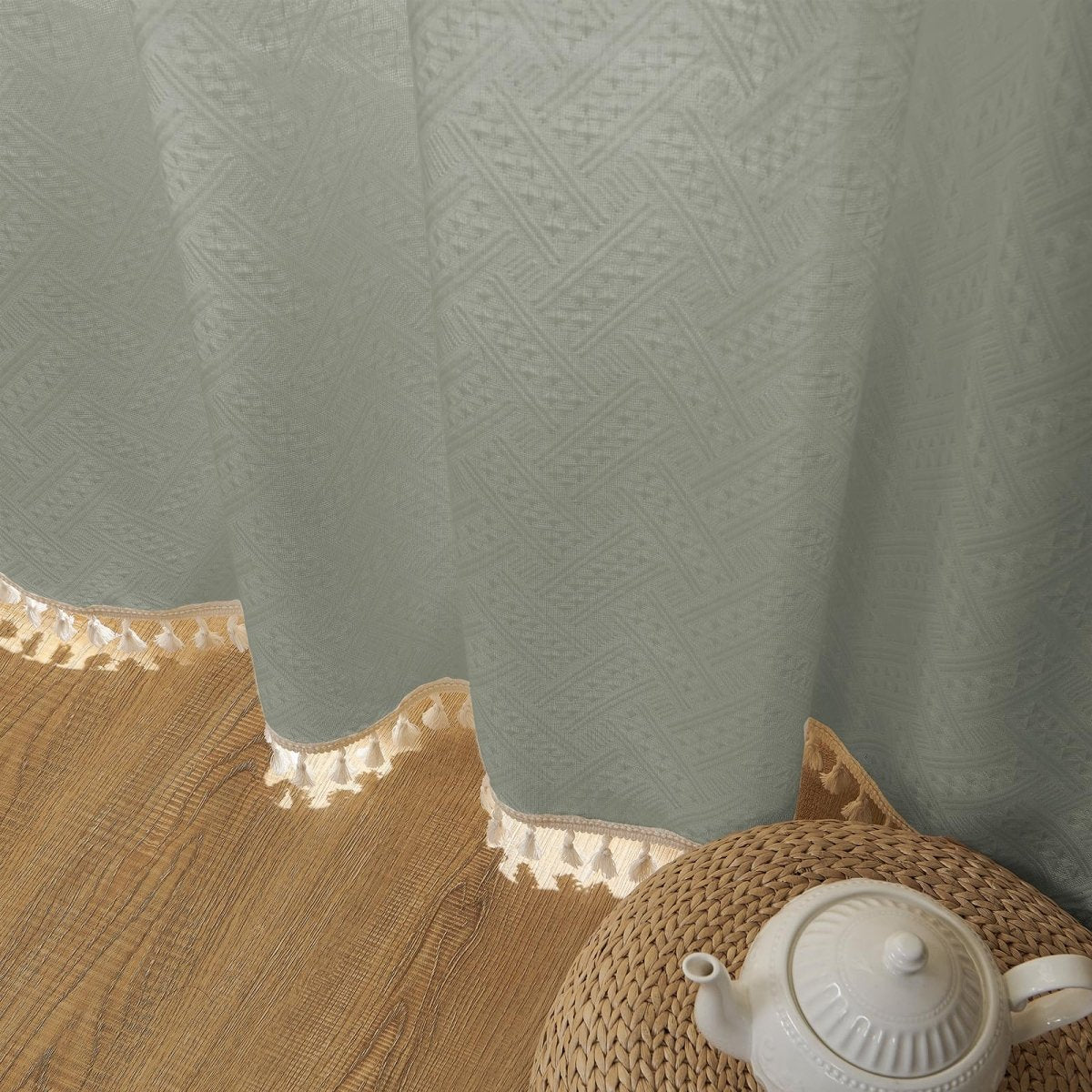 Close-up of sage green boho linen sheer curtain showcasing geometric pattern texture and cream tassel trim.