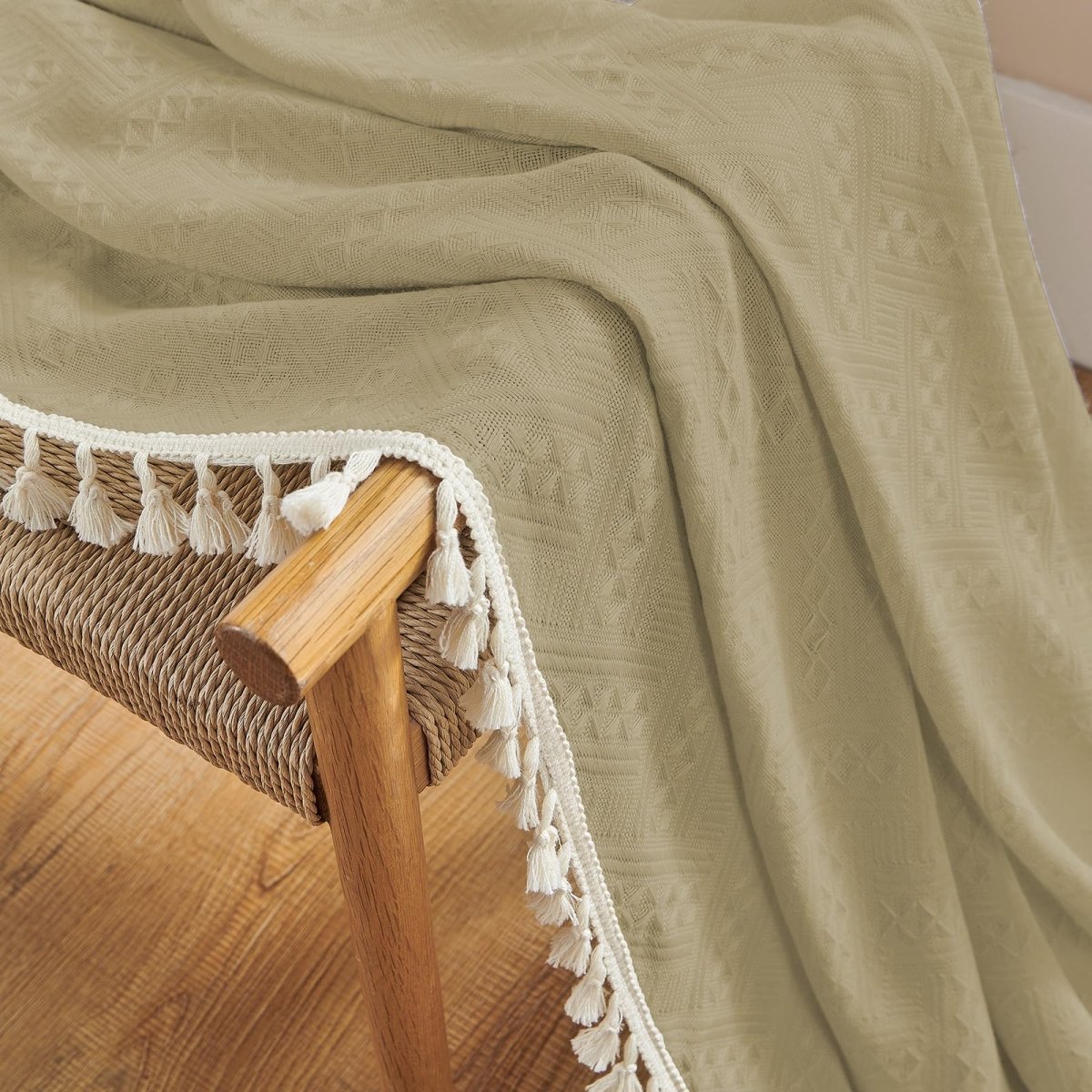 Close up of khaki linen sheer curtain with white tassels, showcasing boho farmhouse texture and country rustic charm.
