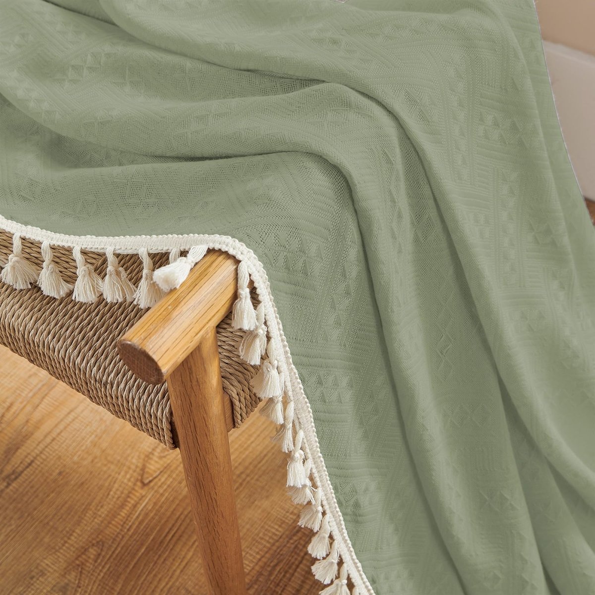 Sage green linen curtains with cream tassels and subtle geometric pattern, boho farmhouse texture detail.