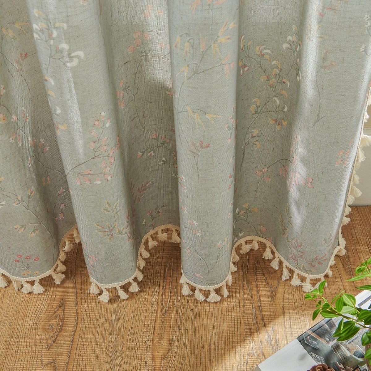 Joydeco light blue sheer linen curtain with pink and yellow floral pattern and cream tassel trim, showing texture.