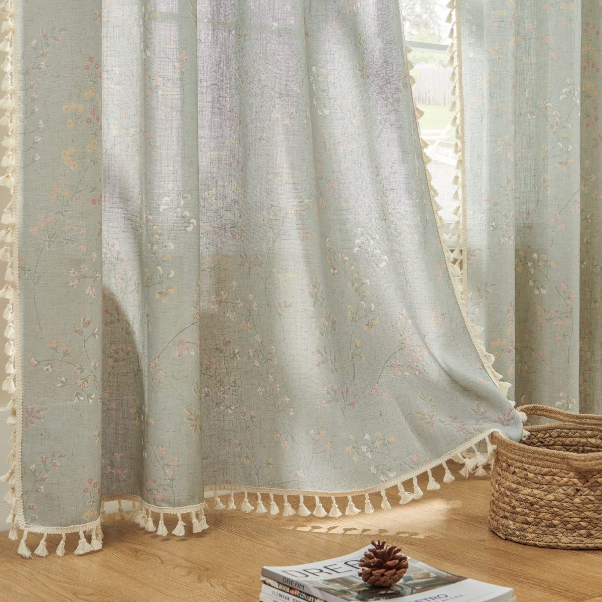 Light blue sheer linen curtains with delicate floral embroidery and cream tassel trim, farmhouse style.
