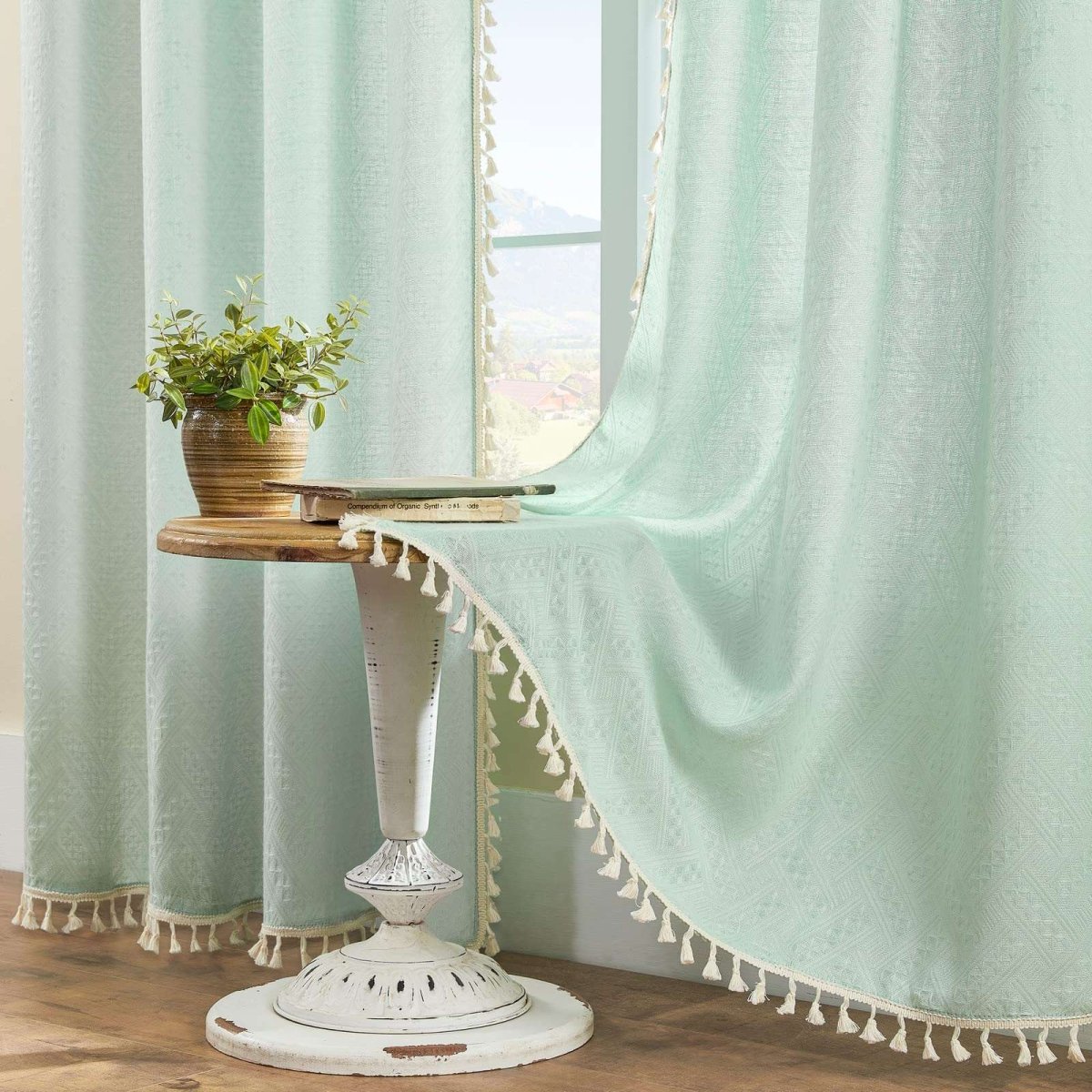 Joydeco mint green boho linen sheer curtains with cream tassel trim displayed on a rod, softening room light.