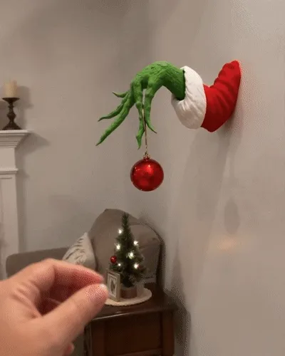 Animated green monster Christmas hand holding red ornament