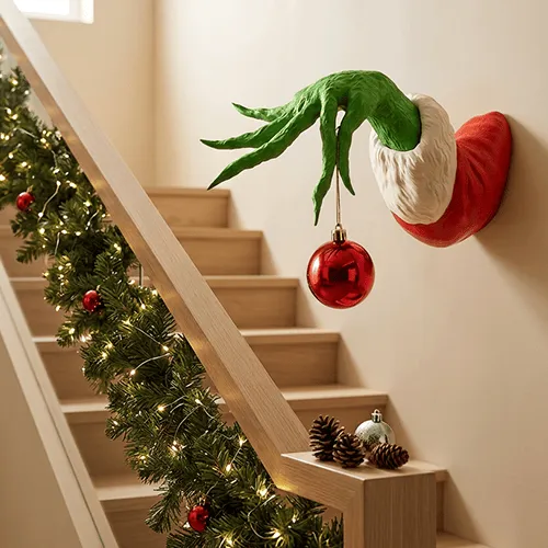 Green monster Christmas hand displayed beside decorated staircase