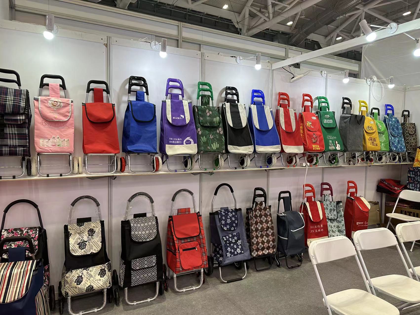 {"default":"A trade show booth featuring an array of folding luggage carts and shopping trolleys neatly arranged on shelves and display stands for visitors to view."}
