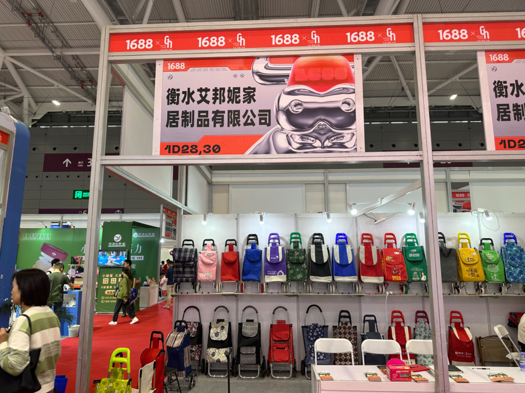 {"default":"A trade show booth displaying various folding luggage carts and shopping trolleys on shelves, with product samples and brochures for visitors."}
