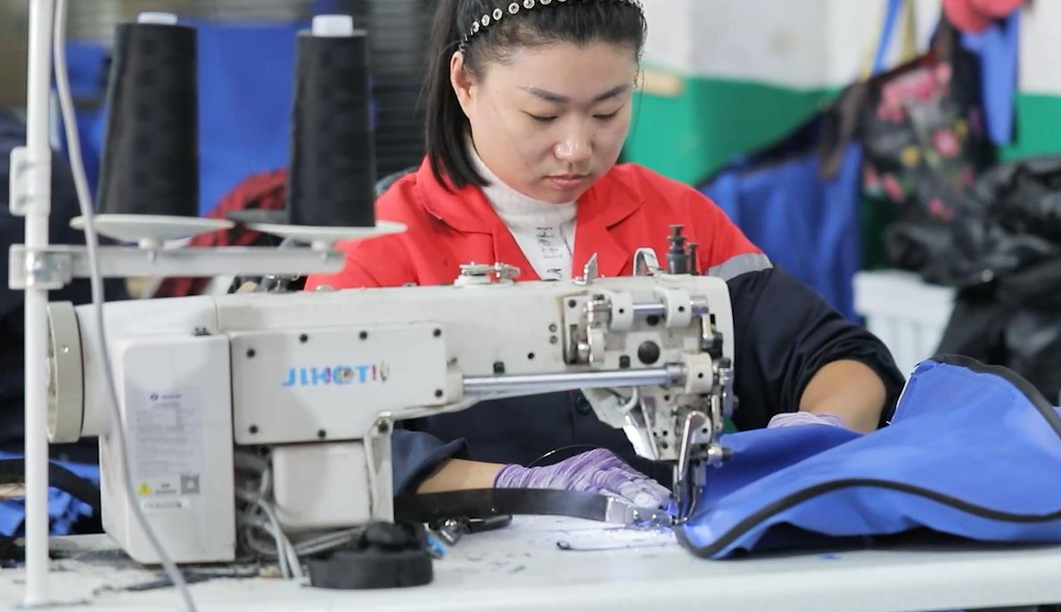 {"default":"A worker sewing fabric on an industrial sewing machine at a factory workstation"}
