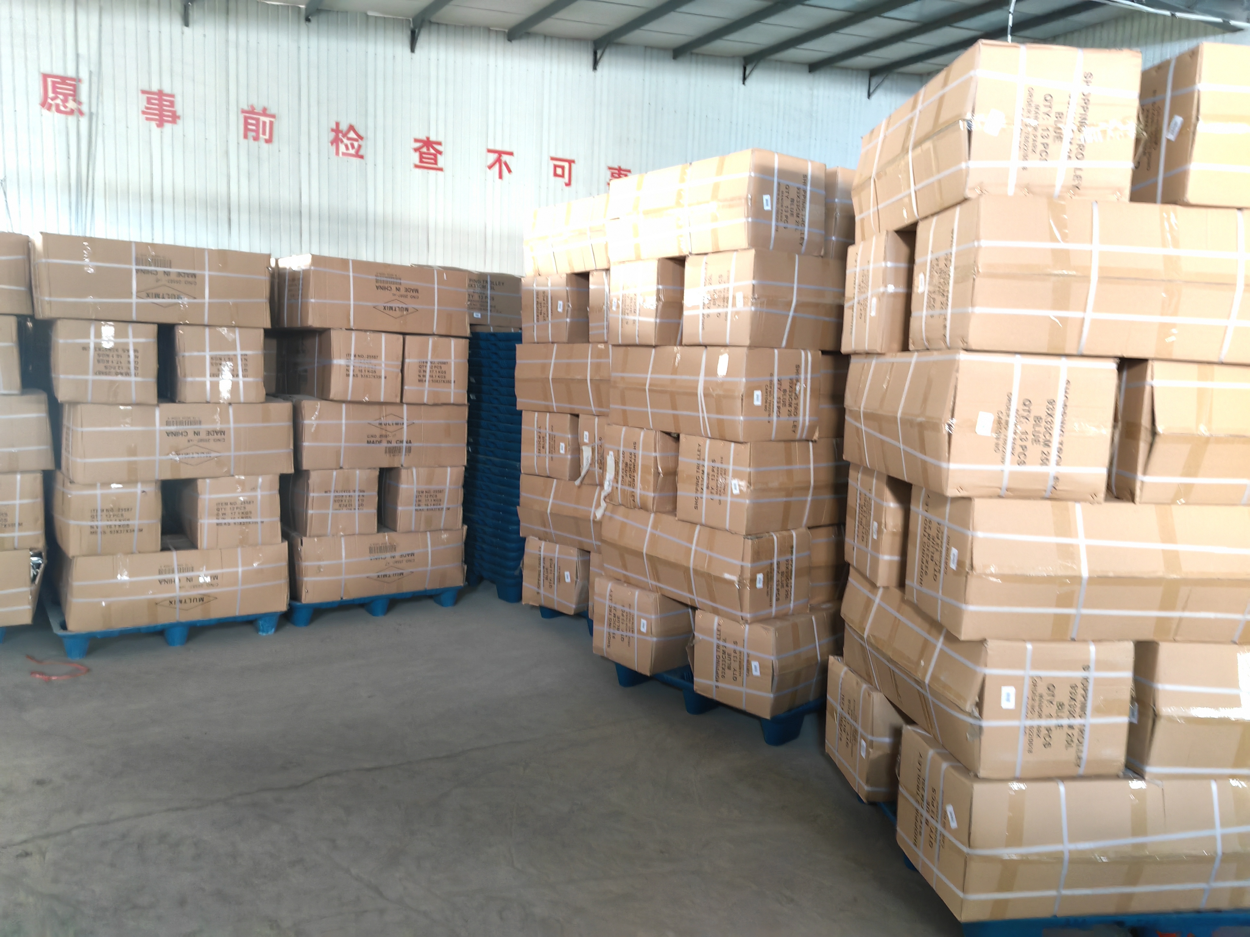 {"default":"Stacks of cardboard boxes secured with straps on blue pallets inside a warehouse, ready for shipping"}
