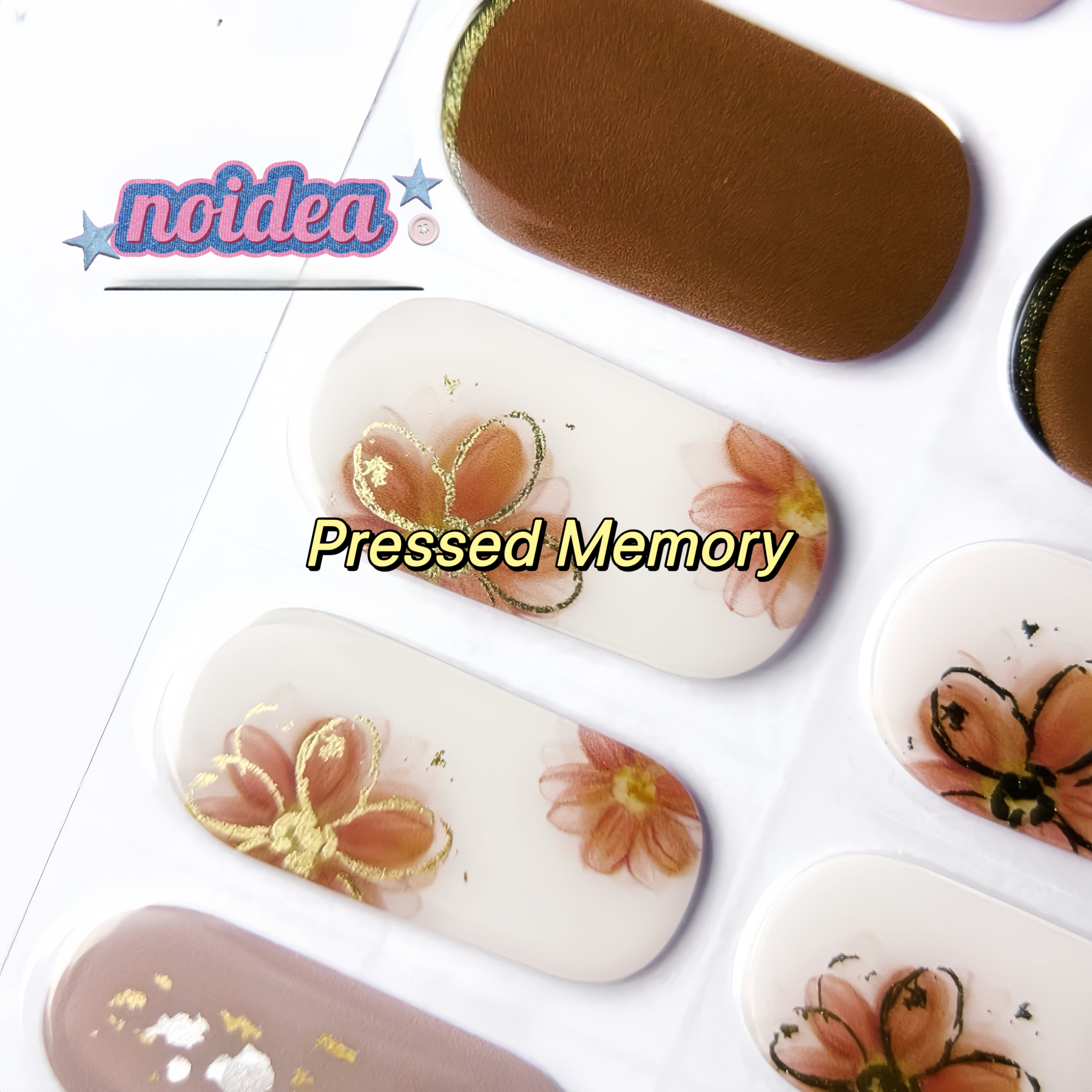 A flat lay of a sheet with 20 metallic gold line floral gel nail stickers on brown and white base