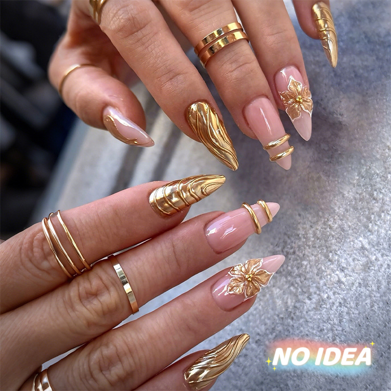 Almond shaped nude pink nails with delicate gold/silver metallic line art forming floral patterns.