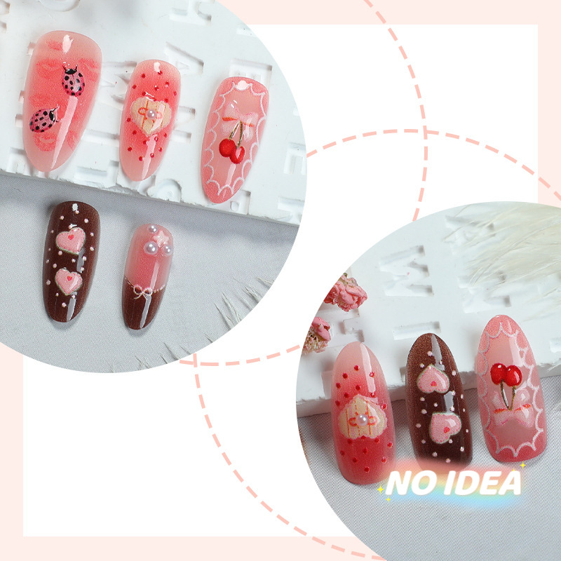 Sweet pink almond shaped nails with cute strawberry, cherry, heart, and bow illustrations.